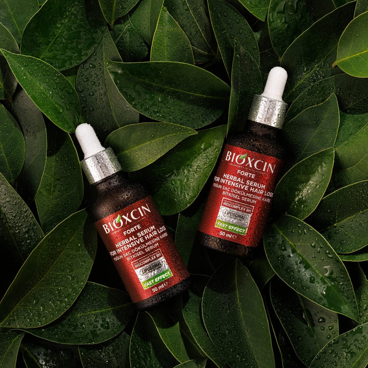 Two bottles of BIOXCIN herbal serum on green leaves